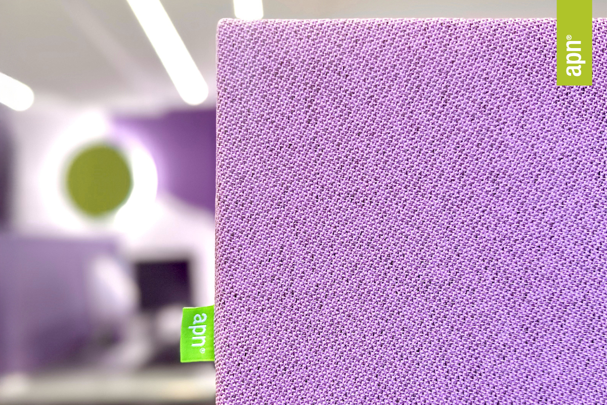 Detailaufnahme eines schallabsorbierenden Akustikelements von apn® in violettem Stoff. Im Hintergrund ein modern eingerichteter Raum mit weiteren akustischen Elementen in Grün und Violett.