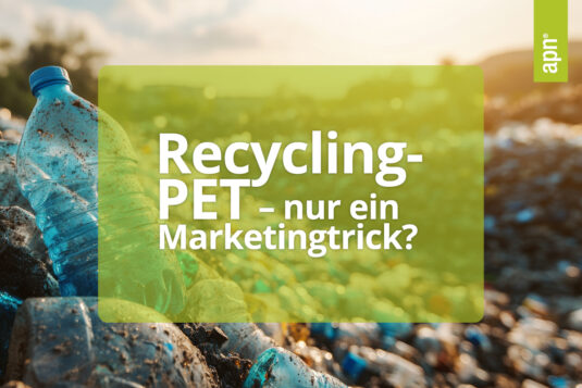 Verschmutzte Plastikflaschen liegen auf einem großen Müllhaufen unter freiem Himmel, im Hintergrund eine unscharfe, natürliche Landschaft mit Sonnenuntergang. Über das Bild ist ein halbtransparenter, grüner Textblock gelegt mit der Aufschrift: ‚Recycling-PET – nur ein Marketingtrick?‘. In der oberen rechten Ecke befindet sich ein senkrechter grüner Balken mit dem Logo ‚apn®‘.
