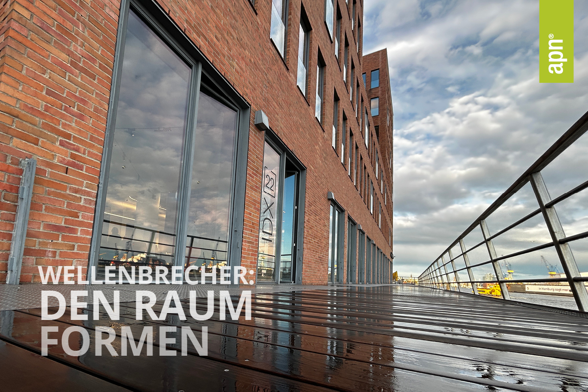 Modernes Gebäude mit markanter Ziegelfassade und großen Glasfenstern, die den bewölkten Himmel auf einer nassen Holzterrasse nach einem Regen reflektieren. Der Schriftzug "WELLENBRECHER: DEN RAUM FORMEN" ist sichtbar.