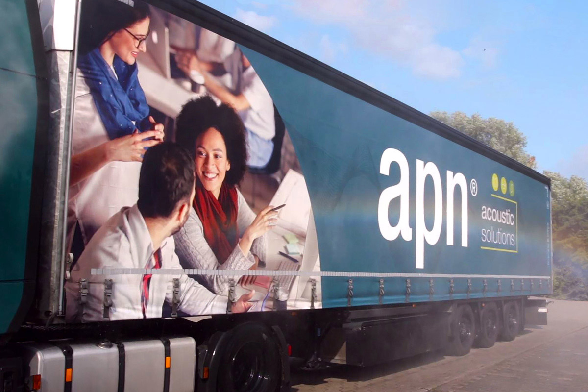 A truck with the apn acoustic solutions logo on the tarpaulin
