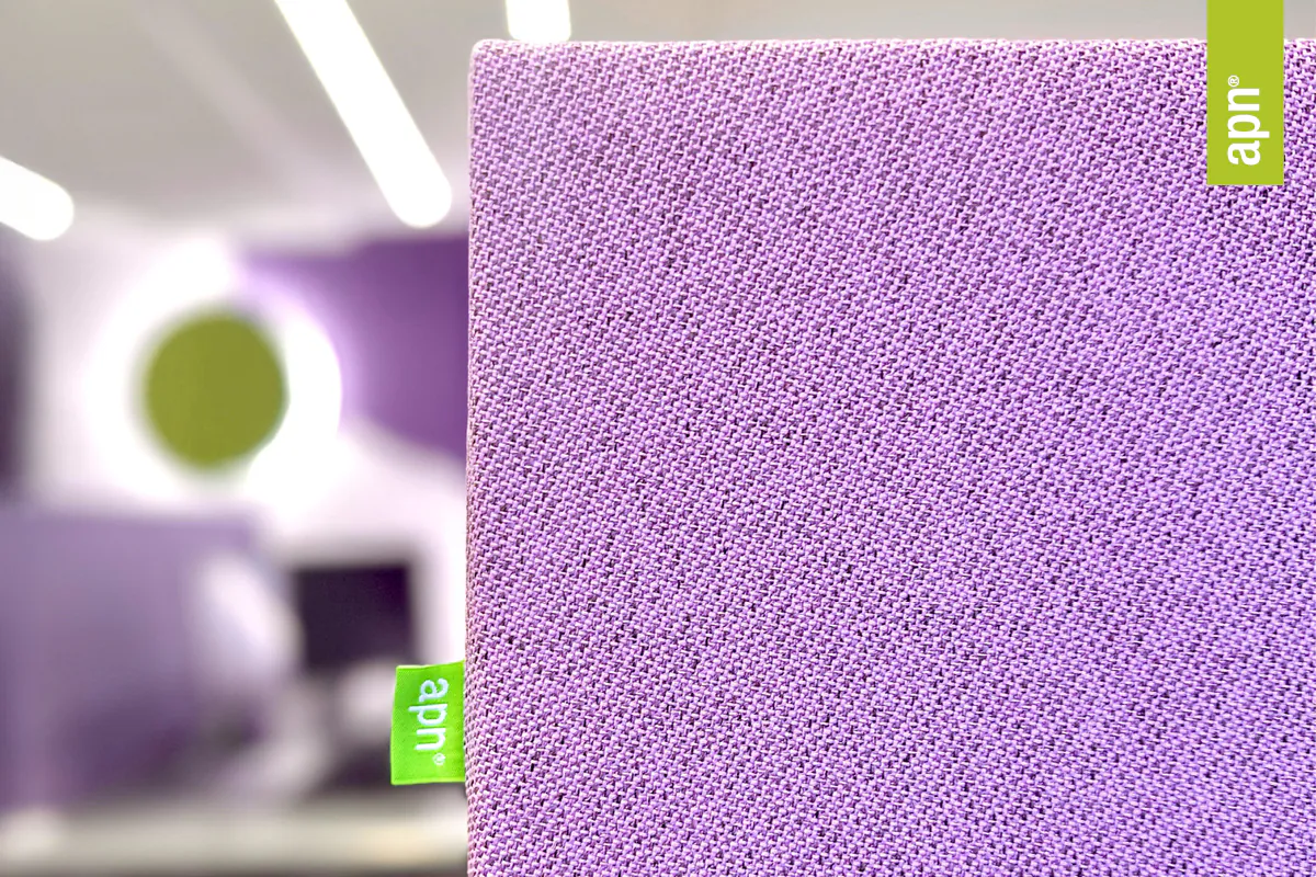 Detailaufnahme eines schallabsorbierenden Akustikelements von apn® in violettem Stoff. Im Hintergrund ein modern eingerichteter Raum mit weiteren akustischen Elementen in Grün und Violett.