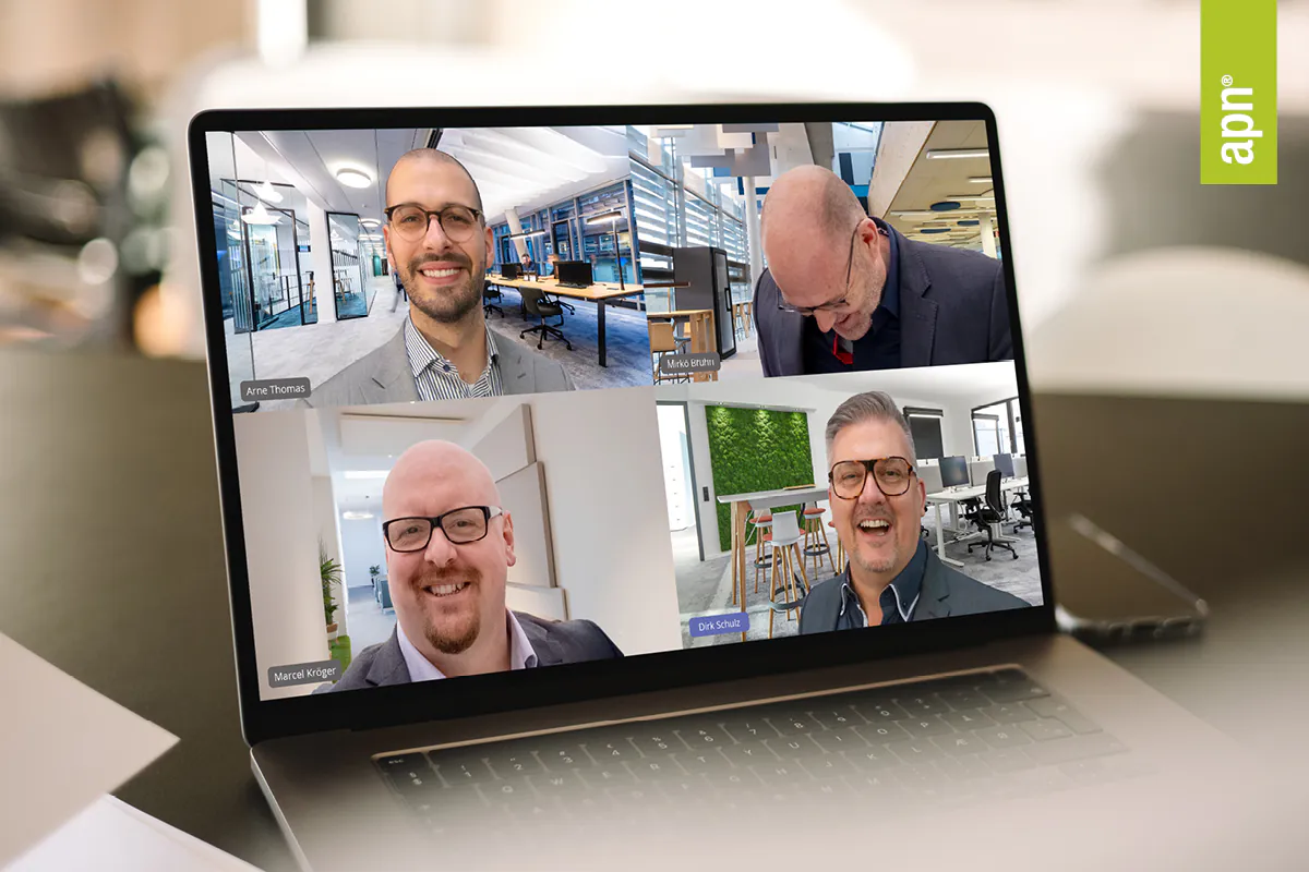 Akustikingenieure. Ein Laptop auf einem Schreibtisch zeigt eine Videokonferenz mit mehreren Teilnehmern. Logo "apn" in der oberen rechten Ecke.