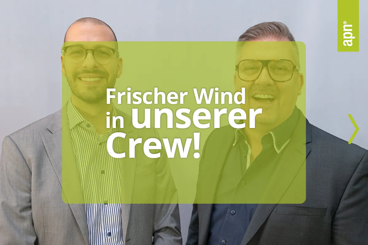 Frischer Wind in unserer Crew ist die Headline in weißer Schrift. Darunter ist eine semitransparente Fläche in Apfelgrün. Im Hintergrund sind zwei Männer zu sehen. Beide tragen Brille. Der Mann links ist anfang 30, trägt ein blau-weiß gestreiftes Hemd und ein hellgraues Sakko. Der Mann rechts trägt ein dunkelgraues Sakko und ein dunkelblaues Hemd