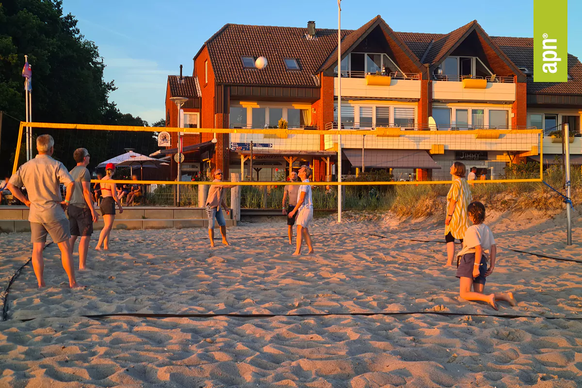 Gruppe spielt Beach Volleyball bei Abenddämmerung